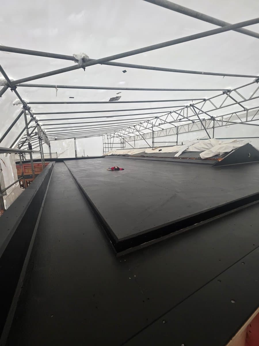 Protected roof installation — Flat roof membrane work completed under temporary weather protection. Membrane Roofing Systems, Auckland NZ.