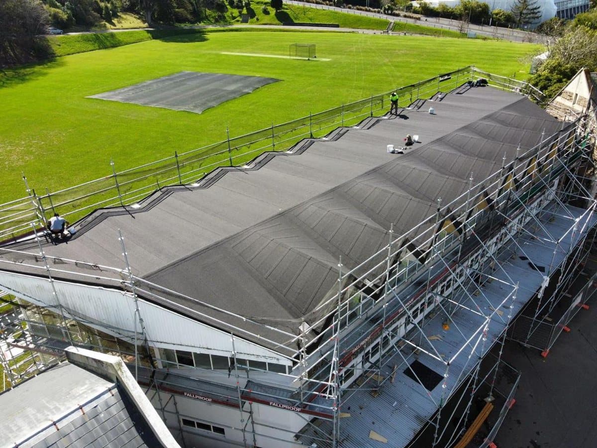 Institutional roofing project — Large-scale membrane roofing system installed with scaffold access. Membrane Roofing Systems, Auckland NZ.